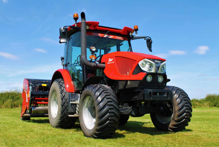 A red tractor set against a field background.