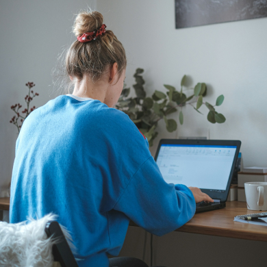 Girl sitting at a desk writing on her laptop.