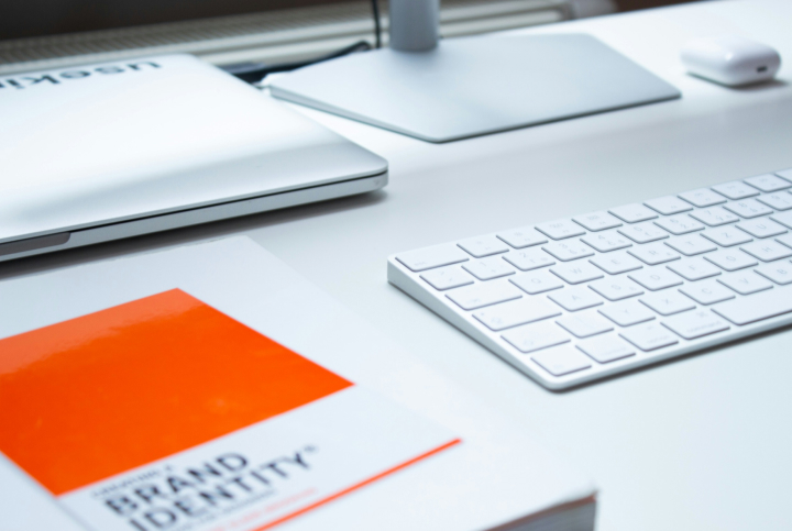 Computer keyboard with a Brand identity book next to it.